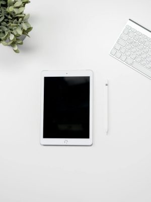 A clean home office desk setup featuring a tablet, keyboard, mouse, and plant for inspiration.