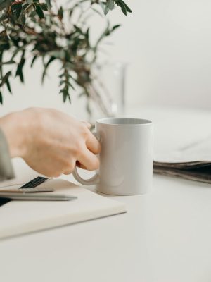 A minimalist workspace featuring a mug, notebook, and greenery, perfect for productivity.